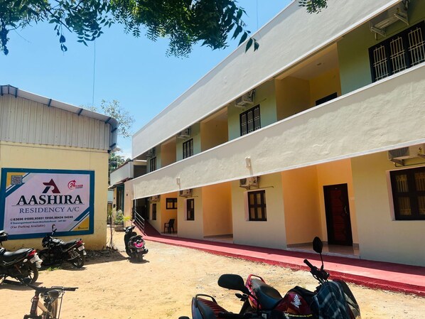 Un edificio residenziale con una targa che indica Aashira Residency con aria condizionata, e segnalazione di parcheggio auto disponibile.