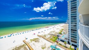 A beach view with a hotel building, a sandy beach, and a clear blue sky. - Phoenix Gulf Shores Ii 1005 4 Bedroom Condo (Gulf Shores)