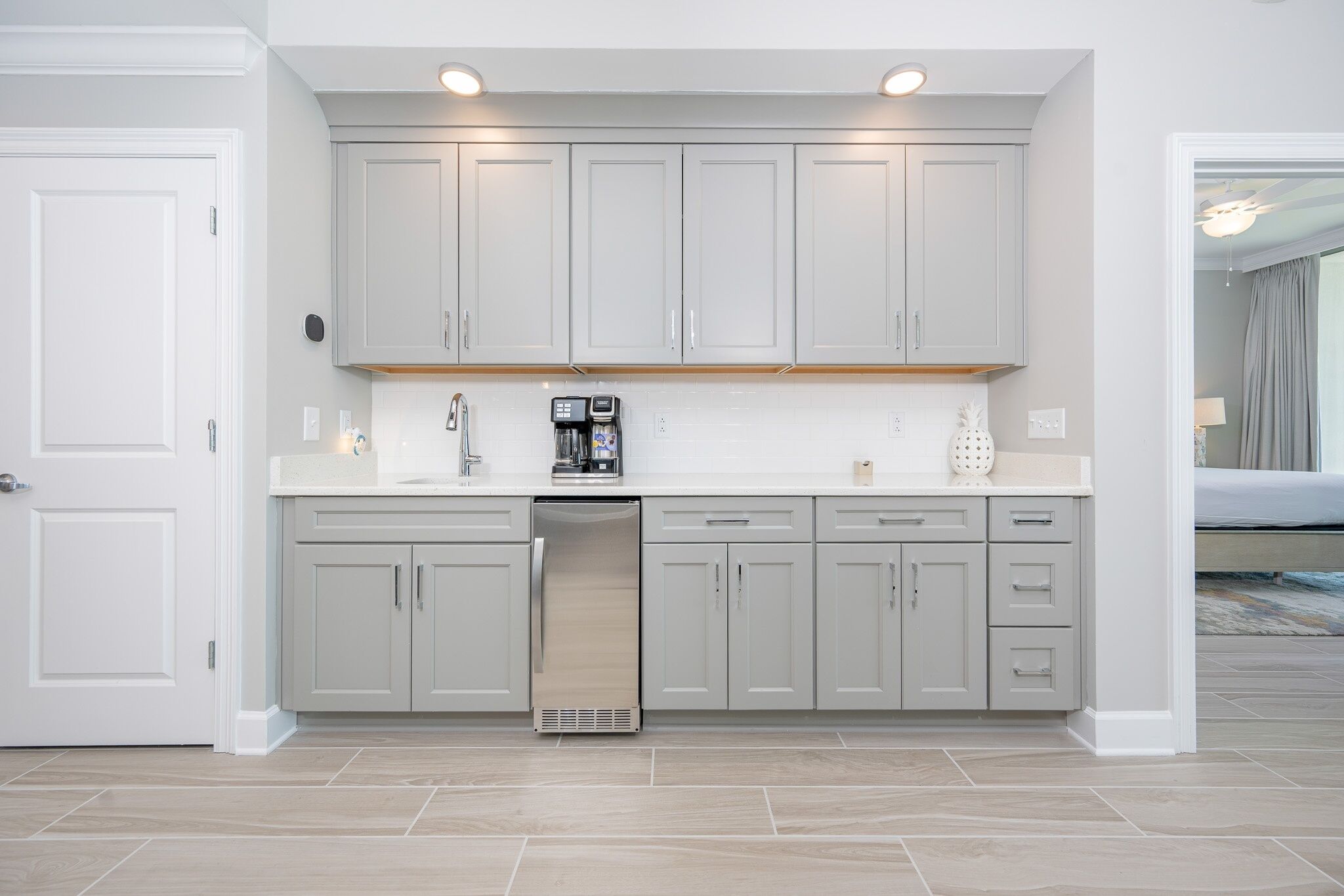 A modern kitchen with grey cabinets, a built-in dishwasher, and a coffee maker.