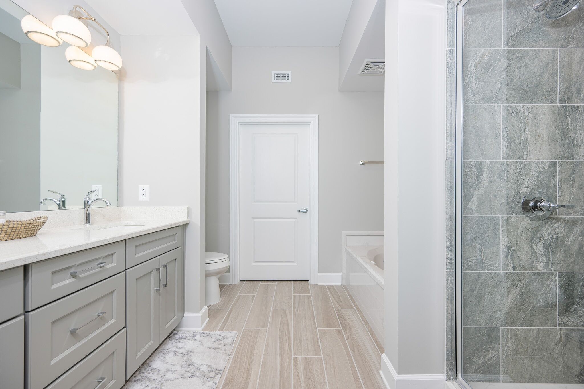 A modern bathroom with a shower, toilet, and sink.