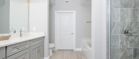 A modern bathroom with a shower, toilet, and sink.