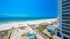 A beach view from a high-rise hotel with a pool and a water slide. - Phoenix Gulf Shores Ii 602 3 Bedroom Condo (Gulf Shores)