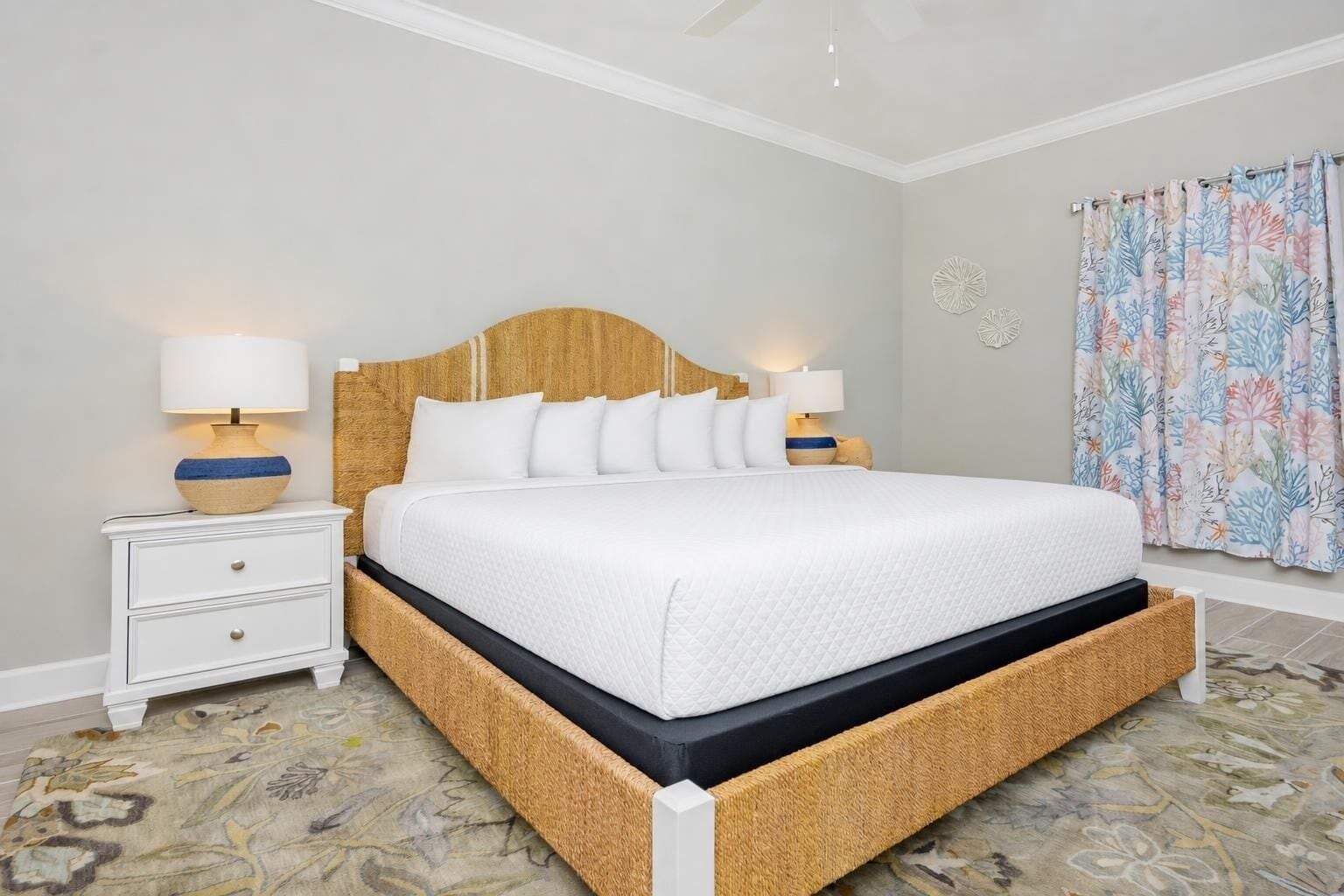 Una cama con cabecera de madera, ropa de cama blanca y dos mesitas de noche con lámparas.