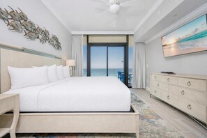 Ein Hotelzimmer mit einem großen Bett, einem Deckenventilator, einem Fernseher, einem Schminktisch und Blick aufs Meer.