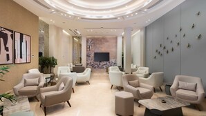 Un hall d’entrée spacieux, doté de mobilier moderne, d’une cheminée centrale et d’un mur agrémenté d’éléments décoratifs.
