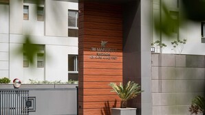 L’entrée d’un hôtel JW Marriott, avec une façade moderne comprenant un panneau en bois et une enseigne indiquant l’emplacement dans le quartier d’Al-Aziz First, à New Cairo.