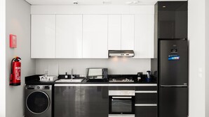 Une cuisine moderne équipée d’un réfrigérateur en acier inoxydable, d’un four encastré, d’un four à micro-ondes et d’un lave-linge.