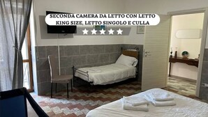 A small, single-bed room with a bed, chair, and a television on the wall. - GranComfort between Naples and Caserta (Castel Volturno)