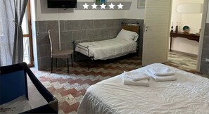 Une petite chambre avec un lit simple, une chaise et un téléviseur fixé au mur.