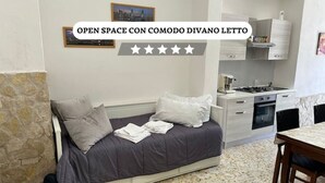 Un dormitorio pequeño con cama, una kitchenette y una pared de piedra.
