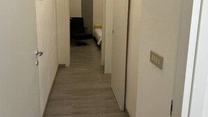 Un pasillo estrecho con suelo alfombrado que conduce a una habitación con cama y sillón.