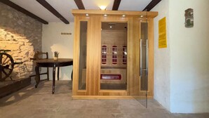 Ein Holzkabinett mit Glastüren, eine Steinwand und ein Tisch mit einem Stuhl.