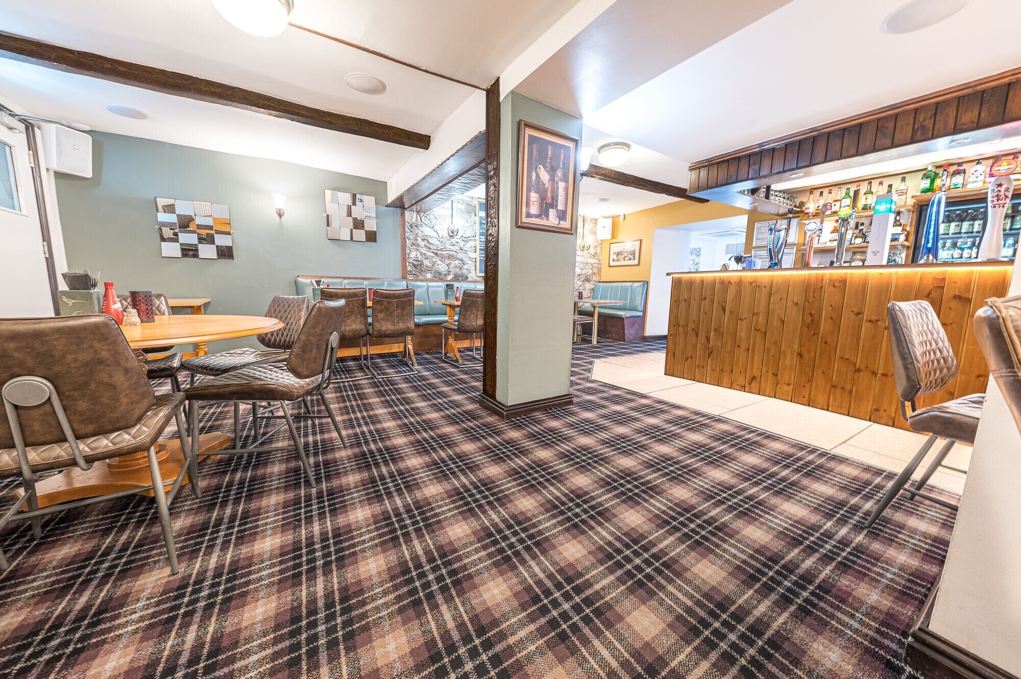A restaurant with a plaid carpet, wooden bar, and seating areas.