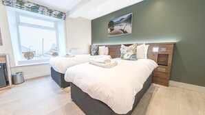 A modern bedroom with two beds, a large window, and a painting on the wall. - The Pheasant Inn (Grange-over-Sands)