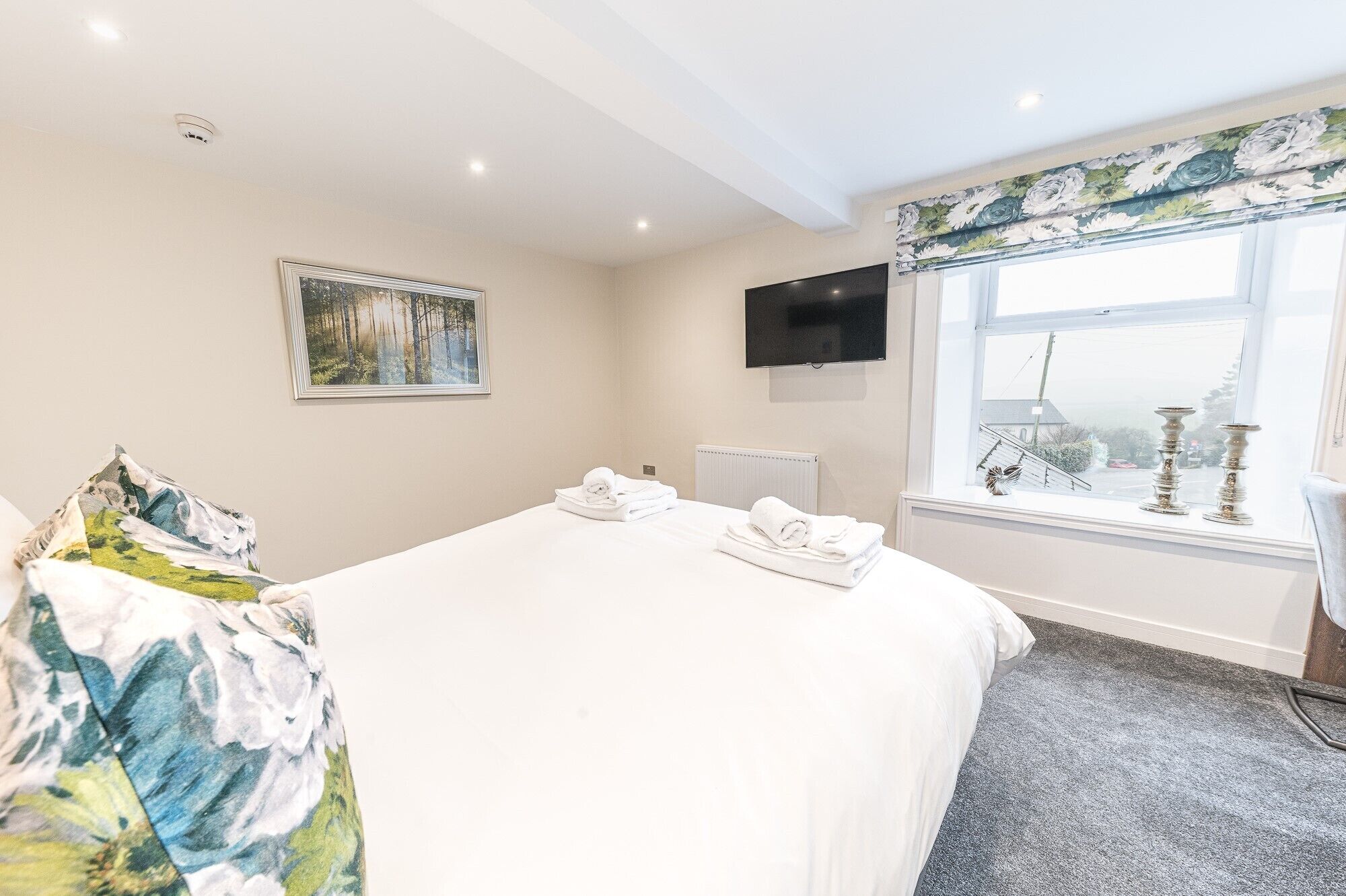 Habitación de hotel con cama, un cuadro, televisor y ventana con vistas.