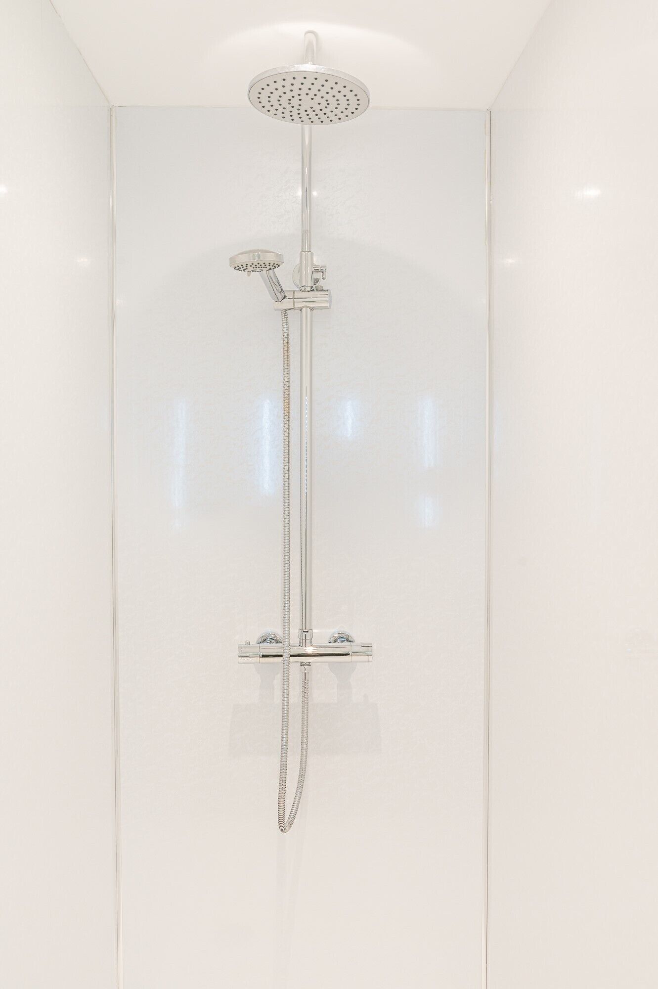 Een moderne douche met een regendouche en een handdouche.