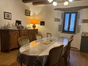 A dining area with a round table, chairs, a wooden cabinet, a lamp, and a window with lace curtains. - Holiday Home 'Angelina' with Wi-Fi (Martrin)