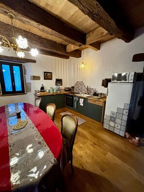 A dining area with a red table and chairs, a kitchen with a microwave and refrigerator, and a window with decorative glass. - Holiday Home 'Angelina' with Wi-Fi (Martrin)