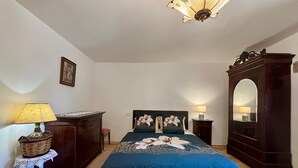 Quarto com cama, mesas de cabeceira, abajur, espelho e um armário de madeira.