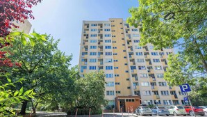 Un edificio residencial de varios pisos con una zona de estacionamiento al frente.