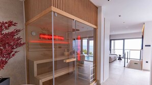 A modern spa room with a glass enclosure, wooden paneling, and a view of the ocean.