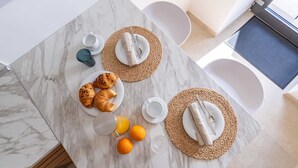 A breakfast setup with croissants, orange juice, and a coffee cup on a marble table.