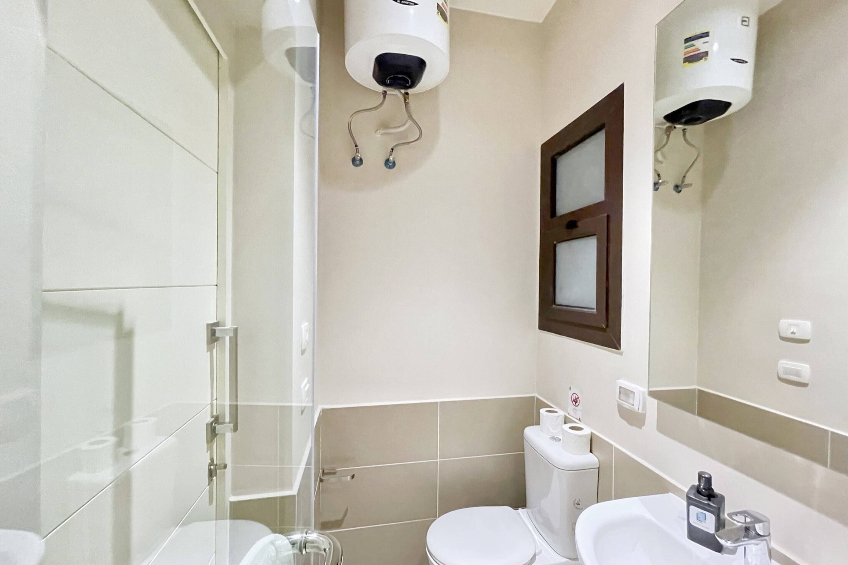 A bathroom with a glass shower enclosure, a toilet, and a sink with a mirror.