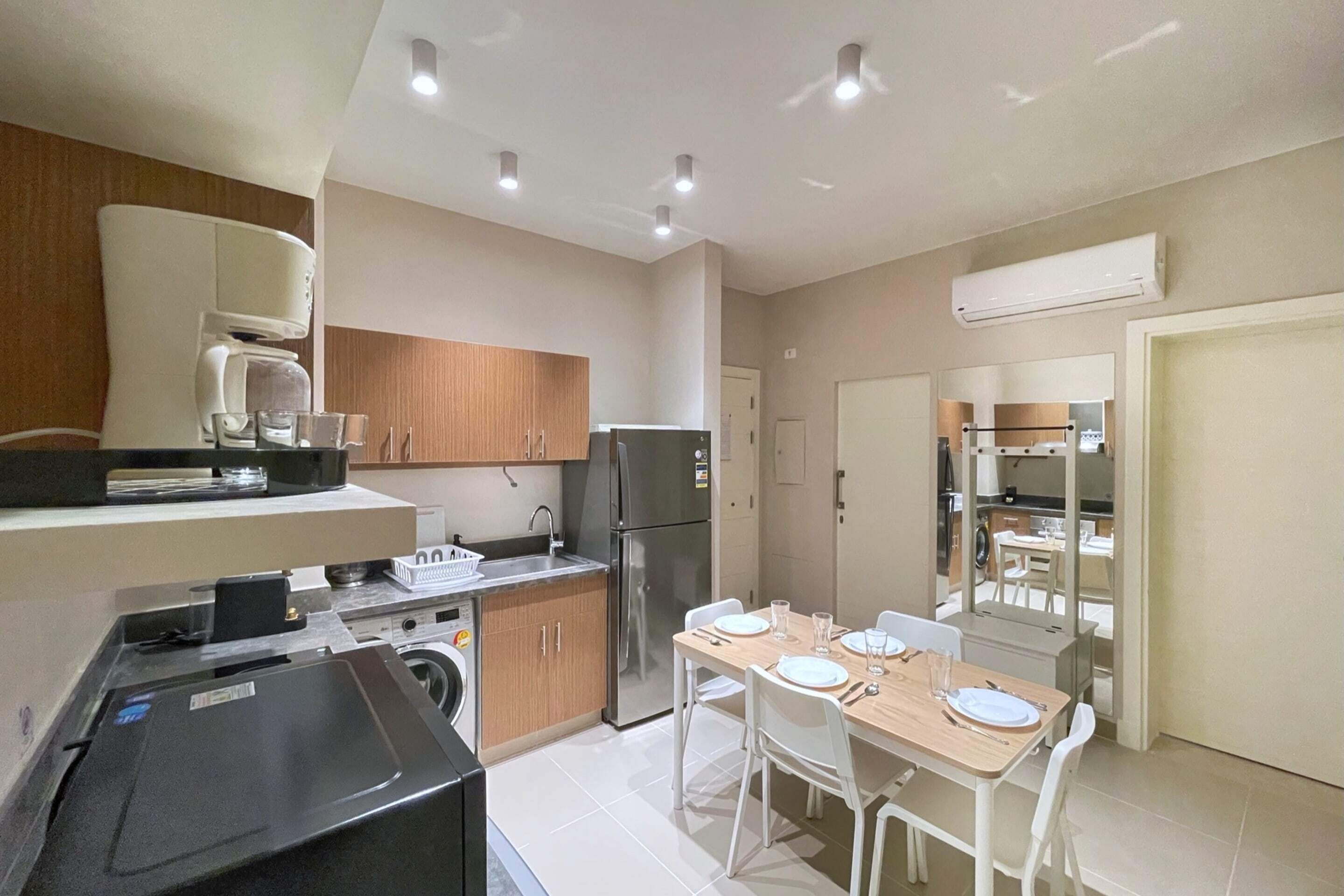 A compact kitchen with modern appliances, a dining area with a table set for four, and a visible laundry machine.