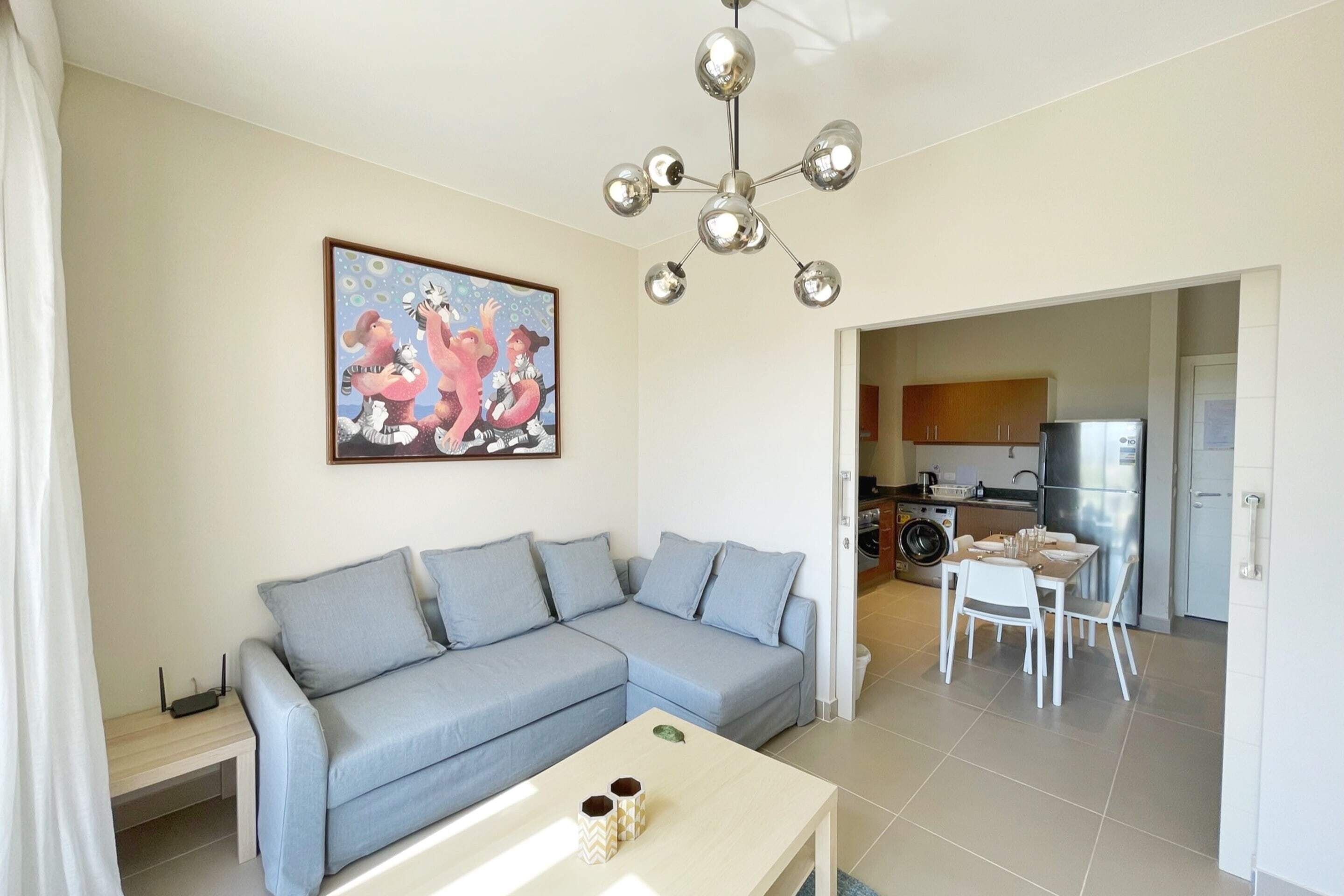 A living room with a grey sofa, a coffee table, and a painting on the wall.
