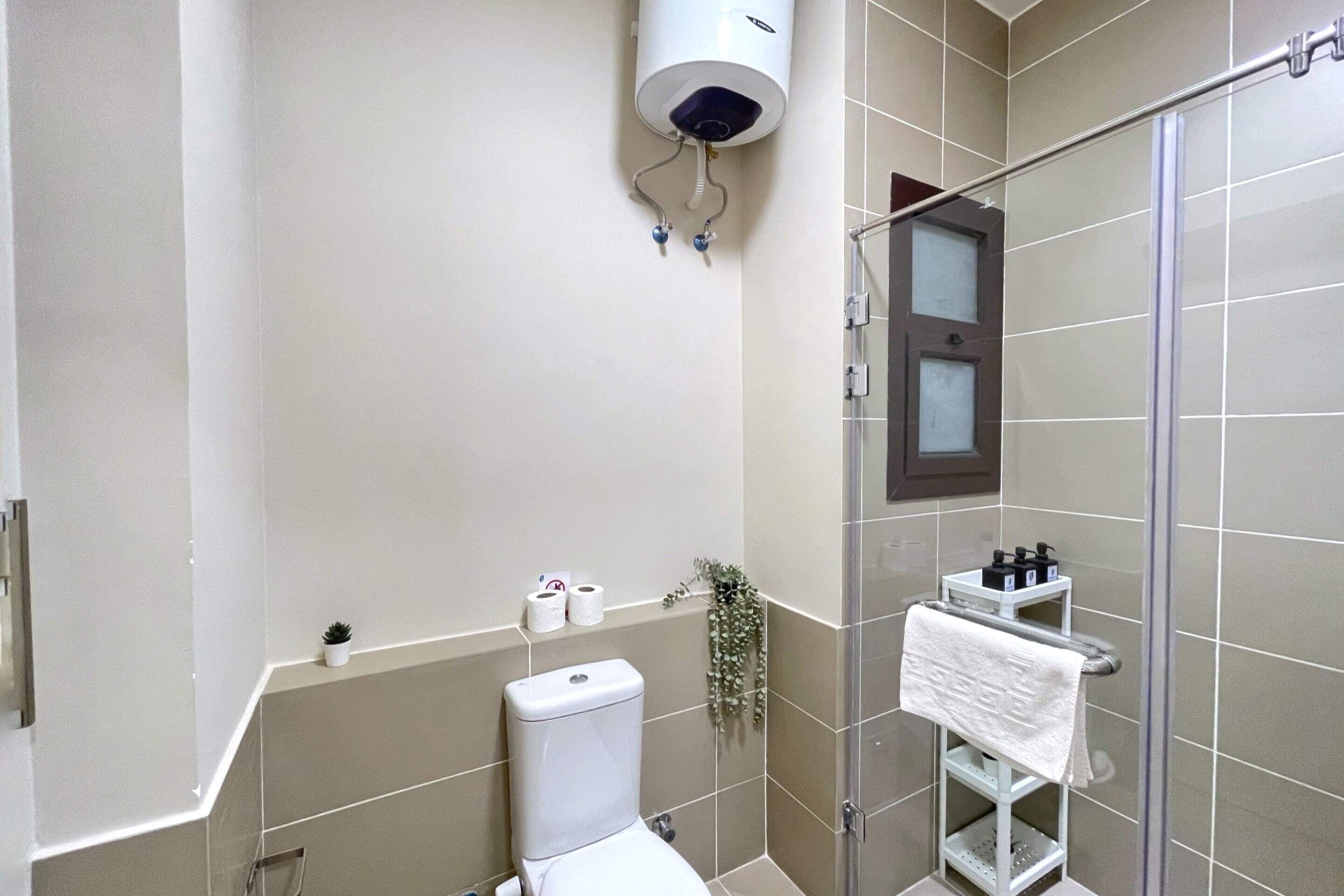 A modern bathroom with a toilet, a shower, and a towel rack.