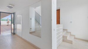 Ein modernes Interieur mit Treppe, Glastür und Blick ins Freie.
