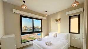 A modern hotel room with a large bed, a window with a city view, and a small desk. - Xuru Stays I Eclectic 2 BDR Twin House @ Tawila El Gouna (El Gouna)