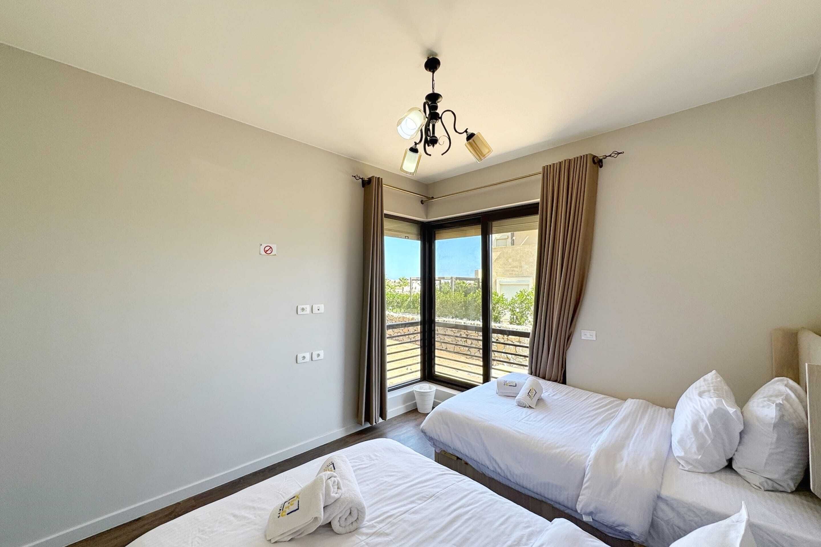 Une chambre d’hôtel avec deux lits, un ventilateur de plafond, une fenêtre avec des rideaux et une vue sur l’extérieur.