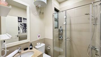 Un baño moderno con ducha de vidrio, lavamanos con toalla e inodoro.