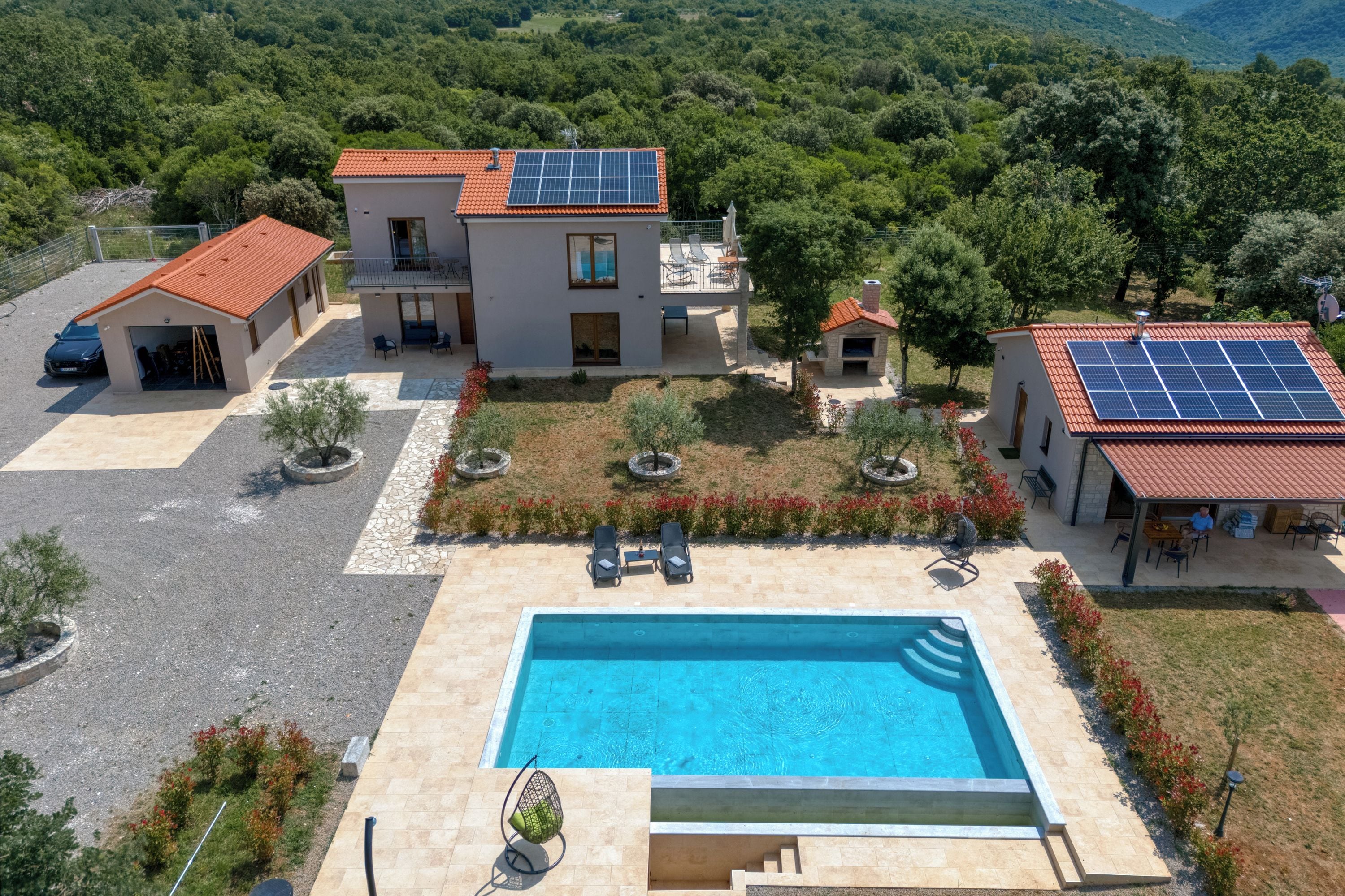 A modern villa with a swimming pool, solar panels, and a lush garden.