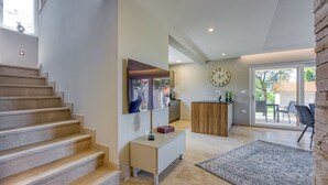 A modern interior with a staircase, a flat-screen TV, a wooden cabinet, and a large clock on the wall. - Villa Tanja Lim Bay (Vrsar)