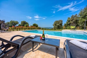 A poolside area with a table, chairs, and a bottle of champagne. - Villa Tanja Lim Bay (Vrsar)