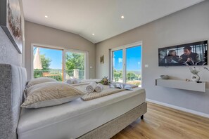 A modern bedroom with a large bed, a TV mounted on the wall, and a balcony with a view. - Villa Tanja Lim Bay (Vrsar)