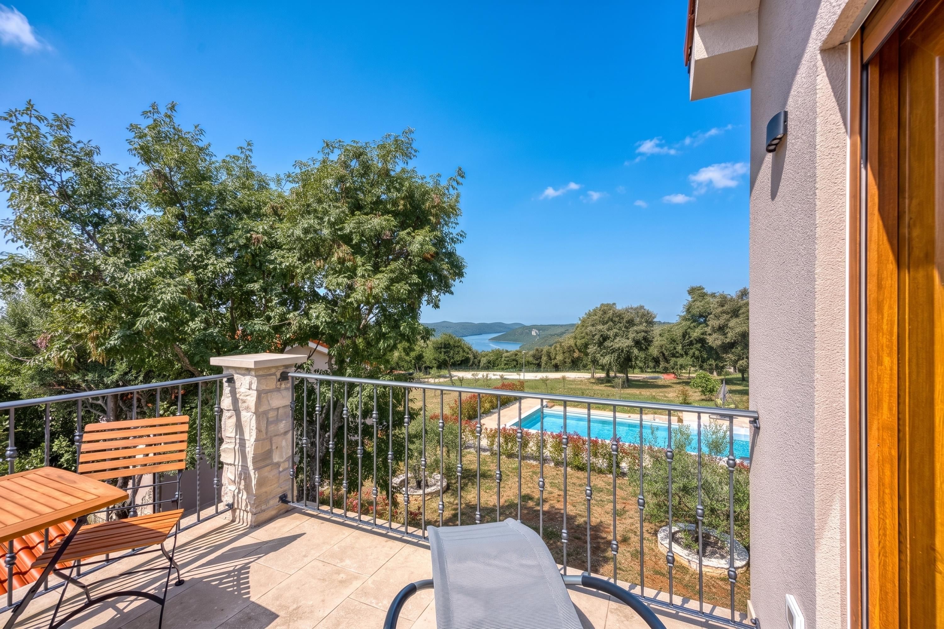 Un balcon avec une piscine, des meubles en bois et une vue sur la mer.