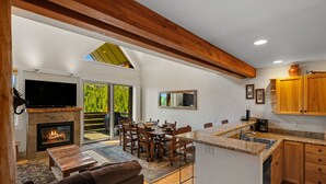 A spacious kitchen with a fireplace, dining area, and a large TV.