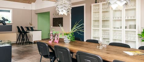 A modern dining area with a wooden table, black chairs, and decorative plants.