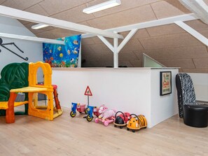 Uma área de recreação infantil com uma estrutura de escalada, uma mesa pequena e diversos brinquedos.