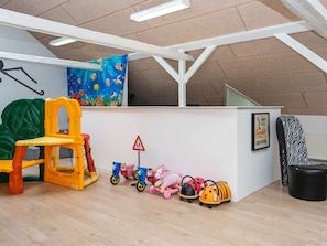 Uma área de recreação infantil com uma estrutura de escalada, uma mesa pequena e vários brinquedos.