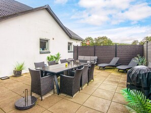 A patio area with a table and chairs, a grill, and potted plants.