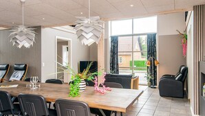 A modern dining area with a wooden table, black chairs, and a decorative plant centerpiece. - 4 Star Holiday Home in Henne (Henne)