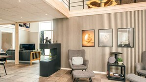 A modern living room with a high ceiling, a fireplace, and a dining area. - 4 Star Holiday Home in Henne (Henne)