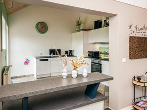 A modern kitchen with white cabinets, a granite countertop, a clock, and decorative vases.