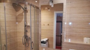 A modern bathroom with a glass-enclosed shower, a white sink, and a mirror above it. - CityCenter ŚLISKA studio (Warszawa)