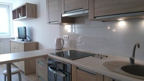 A modern kitchen with wooden cabinets, a built-in oven, a stovetop, and a sink.