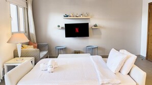 Une chambre d’hôtel avec un lit, un téléviseur fixé au mur, une lampe et une petite table.